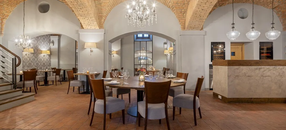 Restaurace Chateau Ctěnice s cihlovými klenbami, lustrem a prostřenými stoly